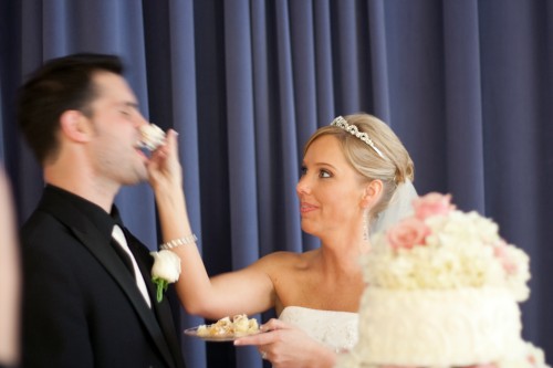 Bride shoving wedding cake into groom's nose