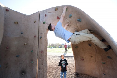 Loren showing off on the climbing wall while a little boy watches