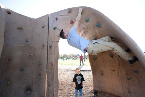 Loren showing off on the climbing wall while a little boy watches
