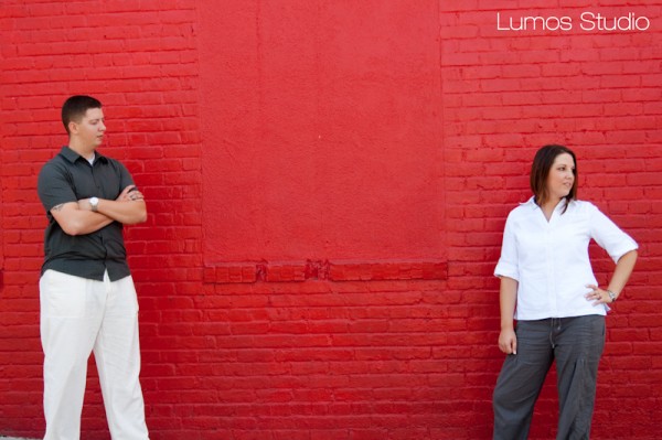 Leah and Greg pose by the bright red brick wall